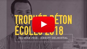 Un homme se tient debout, vêtu d'une chemise à carreaux, en arrière-plan flou de maquettes architecturales. Texte en surimpression : "TROPHÉE BÉTON ÉCOLES 2018 PREMIER PRIX : JÉRÉMY DELHOSTAL". Logo YouTube au centre.