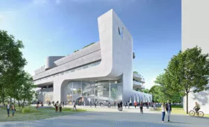 Un bâtiment moderne en béton, avec des formes arrondies, accueille des personnes entrant et sortant. Autour, des arbres et des passants animent l’espace extérieur sous un ciel bleu.