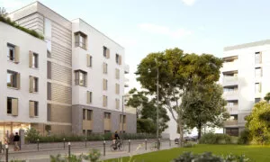 Un immeuble moderne avec des façades en béton beige se dresse au bord d'une rue bordée d'arbres. Un cycliste traverse, encadré par une pelouse verte et d'autres bâtiments.